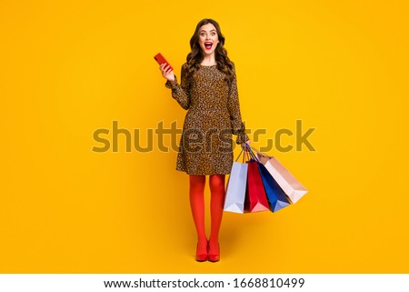 Full length body size view of her she nice attractive lovely glad amazed cheerful cheery wavy-haired girl carrying buyings using cell app isolated on bright vivid shine vibrant yellow color background