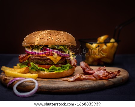 Beef burger and french fries on wooden table isolated on black background