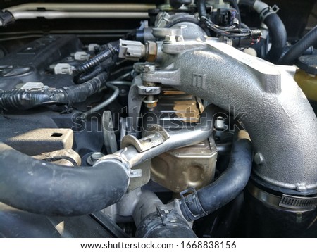 The picture inside the engine compartment of a diesel car consists of a rubber hose and exhaust intake pipe.