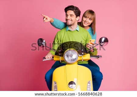 Photo of funny excited lady guy couple two people drive sit vintage yellow moped cool vacation using telephone maps direct finger forward wear casual sweater isolated pink color background
