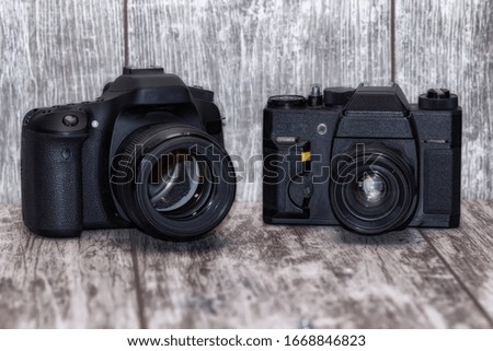 Two cameras on a wooden background : old film and digital SLR