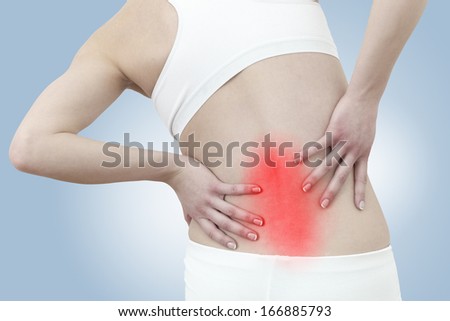 Acute pain in a woman back. Female from behind holding hand to spot of back pain. 