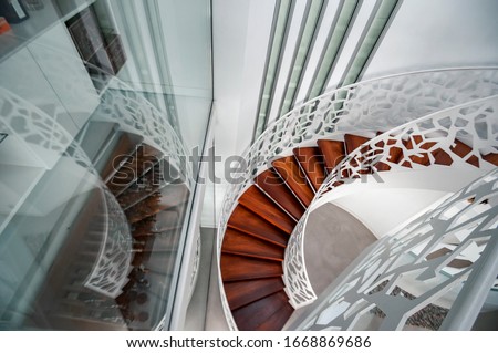 Beautiful white spiral staircase with wooden steps and white iron railings. Selective Focus Photo