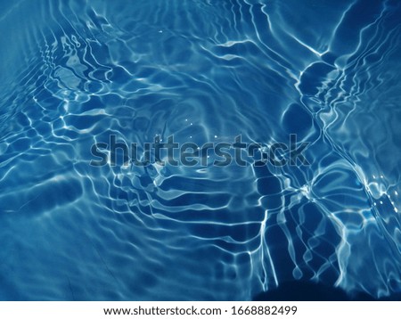 The​ pattern​ of surface​ blue​ water​ in​ the​ swimming​ pool reflected​ with sunlight​ for​ background. Abstract​ on surface​ blue​ water​ for​ background​
