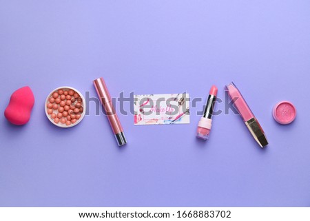 Decorative cosmetics with business card of makeup artist on color background