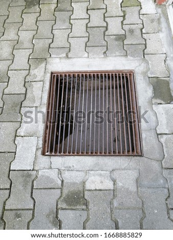 A manhole with a metal covering surrounded by tiles