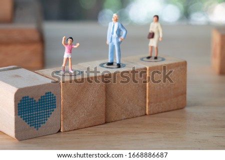 Miniature family on wood block. Son stand in front of his protect parents