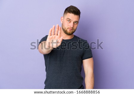 Russian handsome man over isolated background making stop gesture