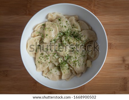 Dumplings filled with mashed potato in bowl on wooden table, high resolution photo .