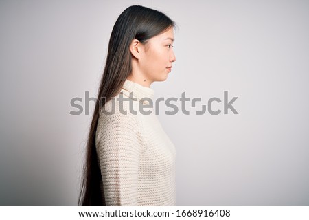 Young beautiful asian woman wearing casual sweater standing over isolated background looking to side, relax profile pose with natural face with confident smile.