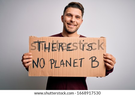 Young activist man holding protest banner for climate change and environment change with a happy face standing and smiling with a confident smile showing teeth