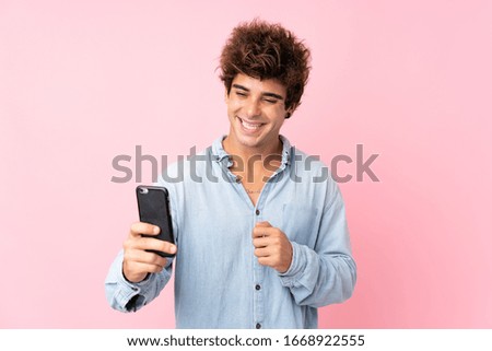 Young caucasian man with jean shirt over isolated pink background making a selfie