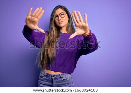 Young beautiful smart woman wearing glasses over purple isolated background doing frame using hands palms and fingers, camera perspective