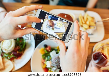 Photographing hands while eating in the restaurant using a mobile phone or smartphone
