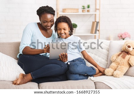 Online Shopping Concept. Cheerful black mom and daughter browsing internet using digital tablet, copyspace