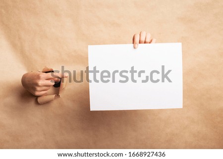Creative idea. Woman pointing finger at empty sheet through torn brown paper, blank space for your design
