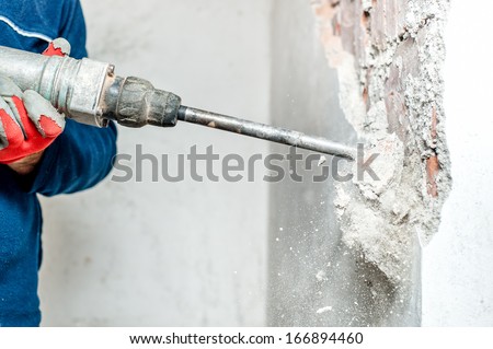 man using a jackhammer to drill into wall. professional worker in construction site Royalty-Free Stock Photo #166894460