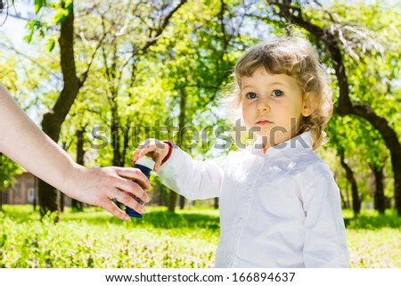 Beautiful little girl blowing soap bubbles in park.