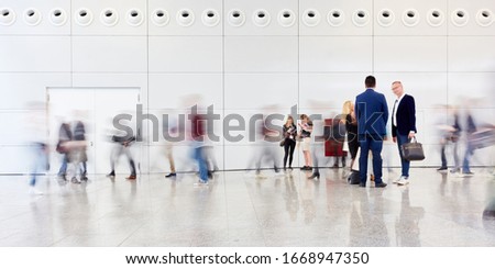 Group of business people is standing in anonymous blurred crowd at a trade fair