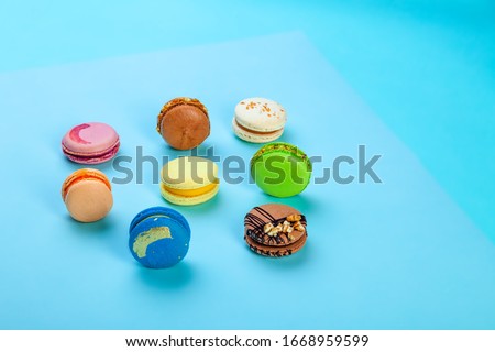 Different types of colorful sweet macaroons dessert on blue background