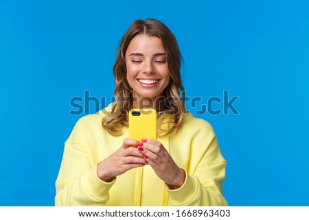 Close-up portrait joyful smiling and entertained caucasian female student attend awesome music concert, record video with mobile phone, taking photo, standing blue background