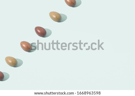 Eggs in shades of brown laing in diagonal line on bright green background with copy space. Trendy Easter pattern.