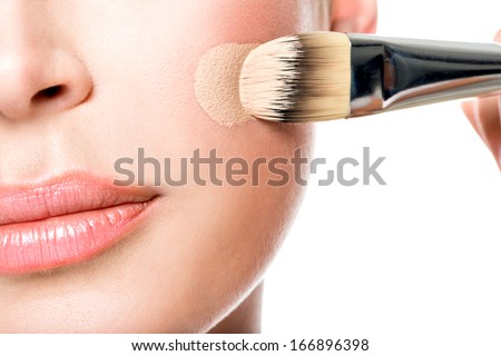 Makeup artist applying liquid tonal foundation  on the face of the woman. Closeup photo of cheek