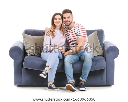 Young couple sitting on sofa against white background Royalty-Free Stock Photo #1668966850