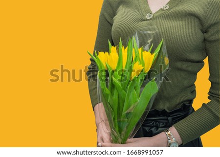 caucasian woman in green blouse holding bouquet of yellow tulips. Gift for holidays.
