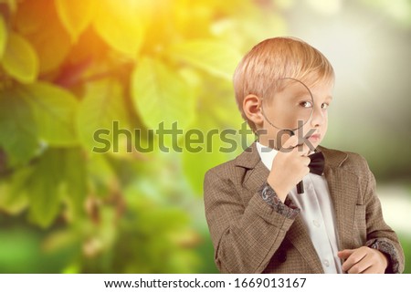 Cute adorable boy looking at plants with a magnifying glass.