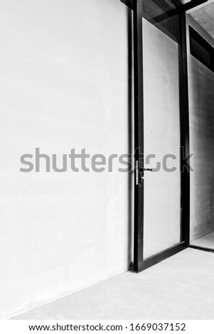 the black glass door on plastered walls with interiors design. That allows sunlight to enter and exit That designed the interior of the architect