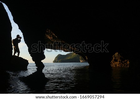 The photographer is using a camera to shoot in a limestone cave by the sea.
