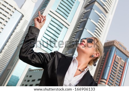 Businesswoman pointing on the skyscraper, cityscape in the background 