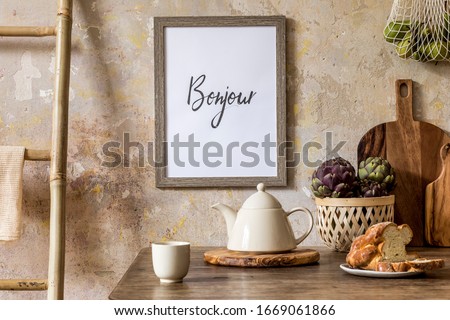 Stylish composition of kitchen interior with wooden mock up frame, family table, ladder, vegetables, tea pot, dessert and kitchen accessories in wabi sabi concept of home decor. 