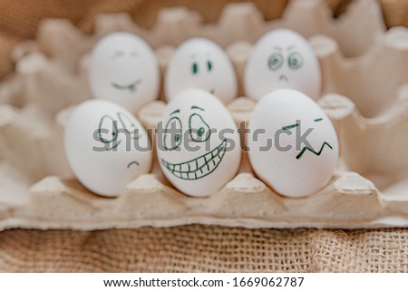 Emotional chicken eggs in a tray. Different  grimaces drawn on chicken eggs.