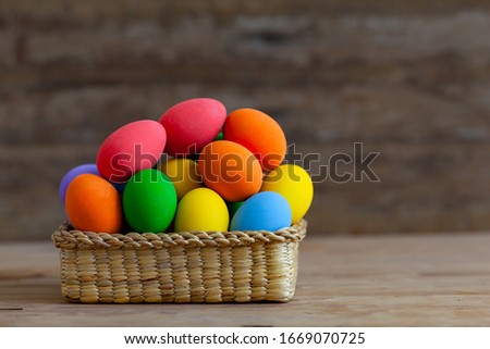 Colorful eggs in a basket placed on a wooden floor at Easter.