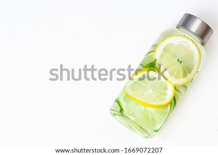 Lemonade with fresh lemon. Lemon and lime water and ice in a glass bottle. White background. Copy space. Concept: healthy life, diet, sport, detox. Drink. 