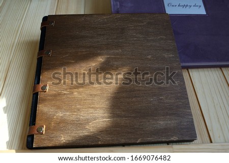 
album photo book with  the inscription
in a brown wooden cover with with a decor next to flowers
