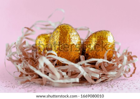 Easter golden decorated eggs in nest on pink background . Minimal easter concept copy space for text. 