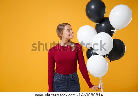 Pretty young woman girl in casual clothes posing isolated on yellow orange background. Birthday holiday party, people emotions concept. Mock up copy space. Celebrating holding colorful air balloons