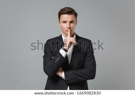 Secret young business man in classic suit shirt posing isolated on grey background. Achievement career wealth business concept. Mock up copy space. Say hush be quiet with finger on lips shhh gesture Royalty-Free Stock Photo #1669082830