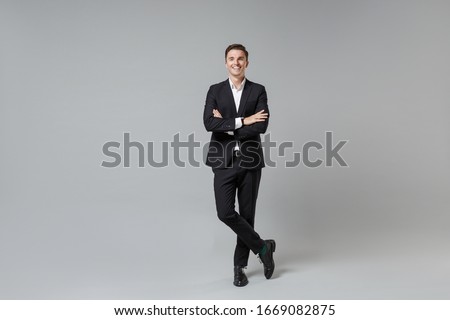 Cheerful young business man in classic black suit shirt posing isolated on grey wall background studio portrait. Achievement career wealth business concept. Mock up copy space. Holding hands crossed Royalty-Free Stock Photo #1669082875