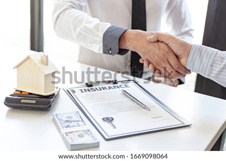 Both businessmen shake hand to congratulate them on their successful signing of a contract with a home insurance agent, housing purchase and insurance Concept.