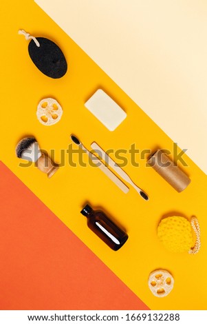 Group of eco cosmetics products and tools for shower, vertical picture with yellow and orange background.