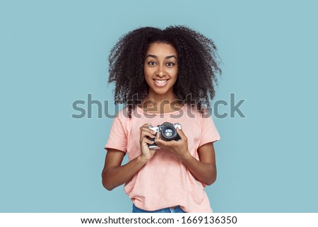 Young african girl standing isolated on gray background holding film camera smiling excited