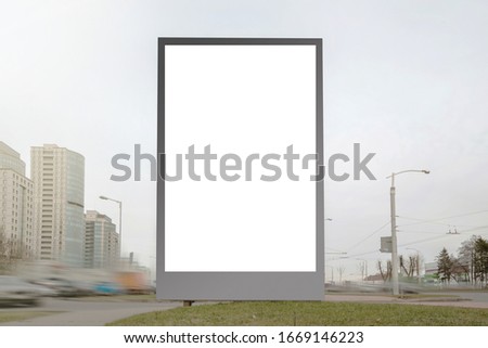 huge white blank advertising board with space for template on modern city street near road with cars on spring day