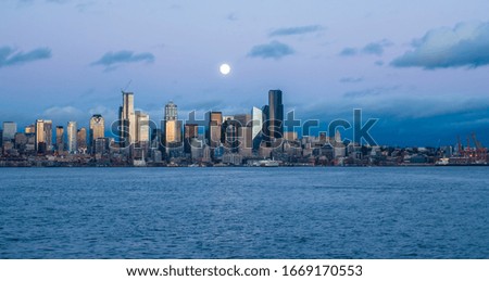 A full moon shines above the Seattle skyline.