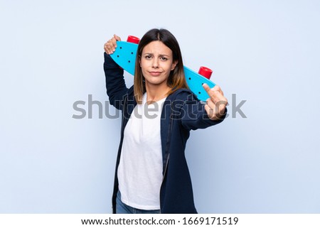 Young woman over isolated blue background with skate