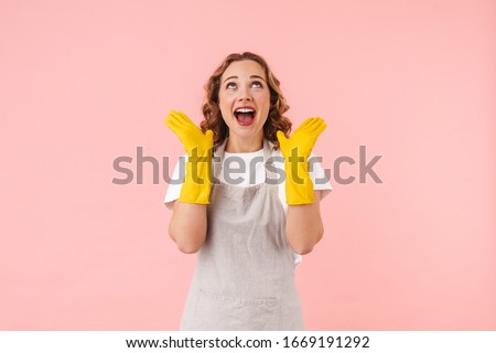 Picture of surprised excited woman housewife isolated over pink wall background in gloves.