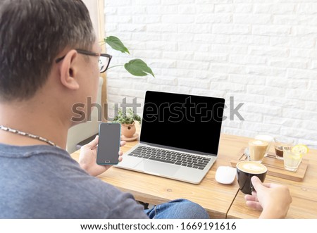 Asia middle age freelance working on laptop at restaurant or cafe. The blank screen with copy space for your text or advertising content. Clipping path on picture.